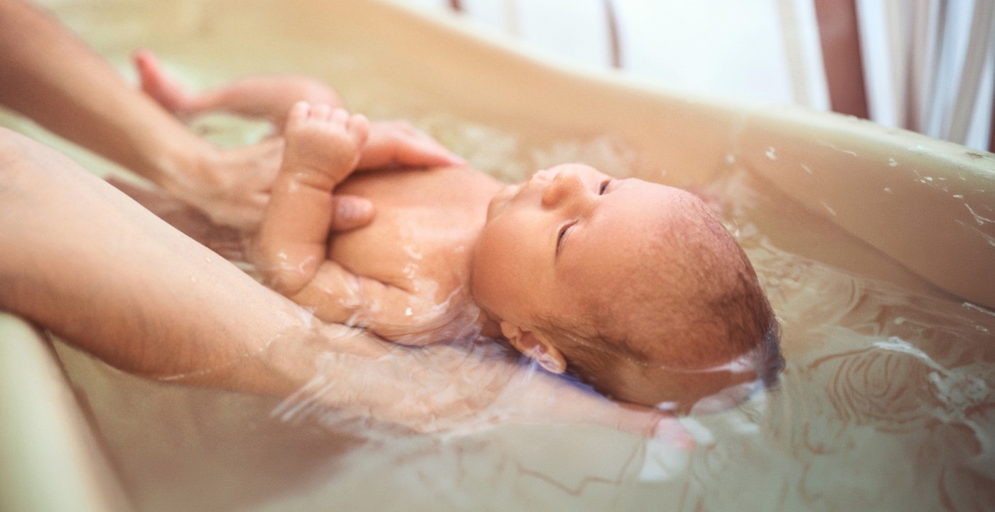 Bébé prenant son bain avec l’aide d’un parent