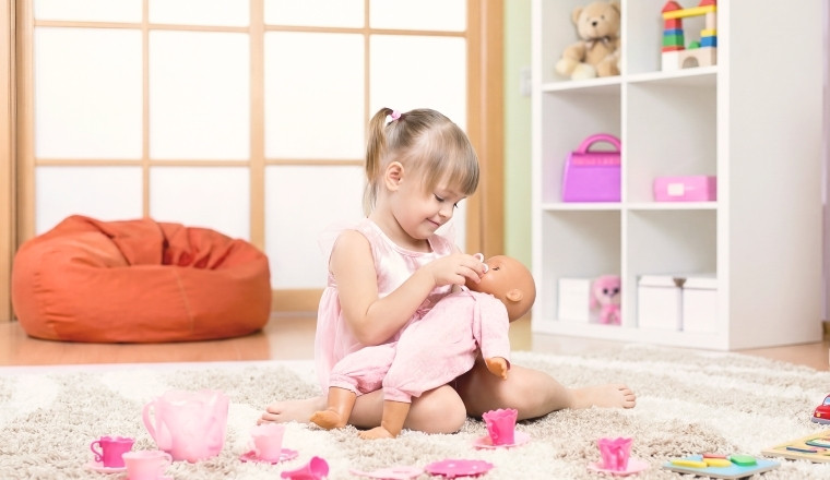 Petite fille jouant avec un poupon dans une chambre d’enfant