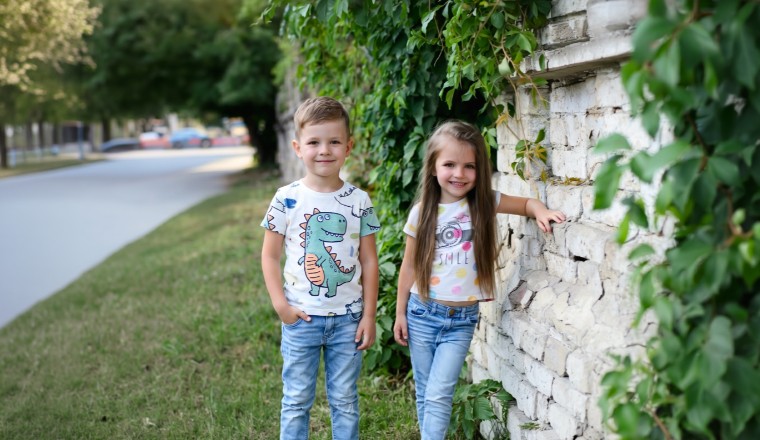 Deux enfants souriants debout près d'un mur végétalisé en extérieur