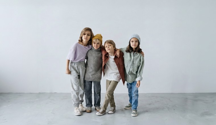 Quatre enfants en vêtements aux tons doux dans une ambiance mode et minimaliste