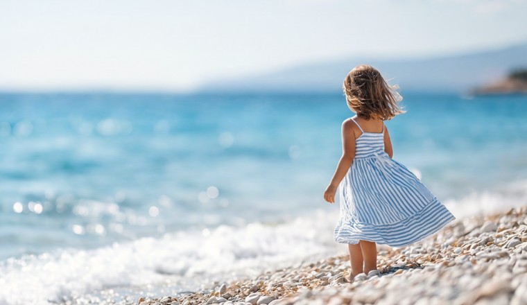 Enfant en robe légère rayée sur une plage en été