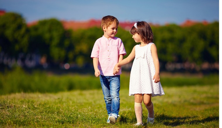 Garçon et fille marchant main dans la main dans un parc ensoleillé