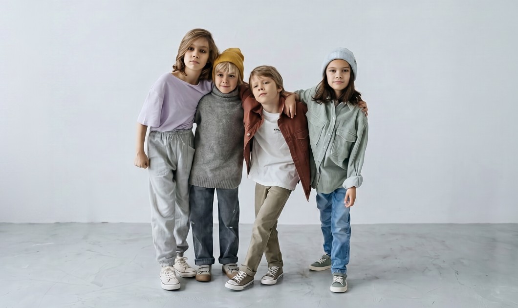 Quatre enfants en vêtements aux tons doux dans une ambiance mode et minimaliste