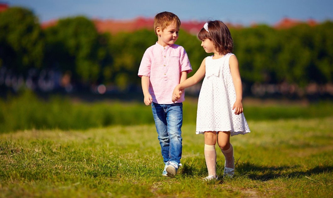 Garçon et fille marchant main dans la main dans un parc ensoleillé
