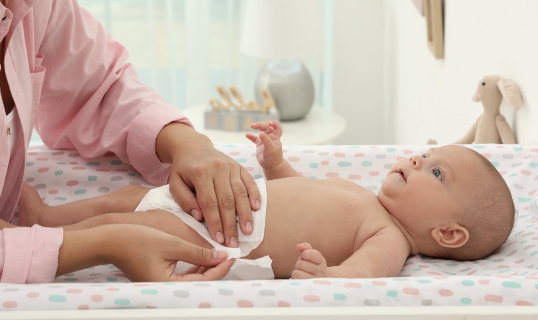 Maman changeant son bébé sur une table à langer dans un moment de soin et de complicité