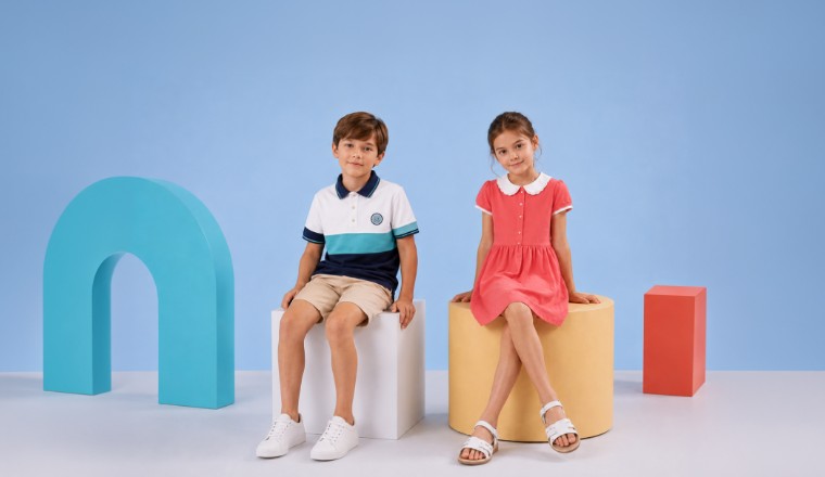 Garçon et fille assis dans un studio aux décors géométriques portant une collection de vêtements d'été élégants